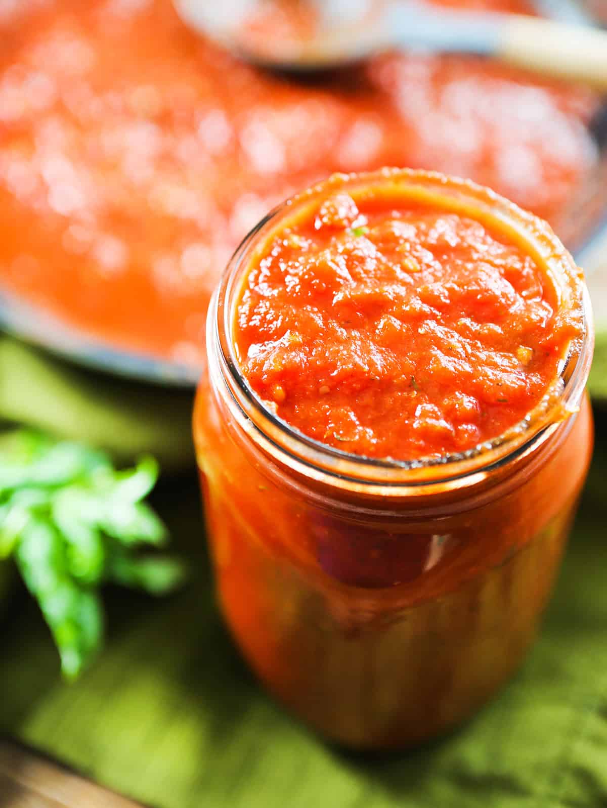 Marinara sauce in a mason jar, next to a skillet filled with the tomato mixture.
