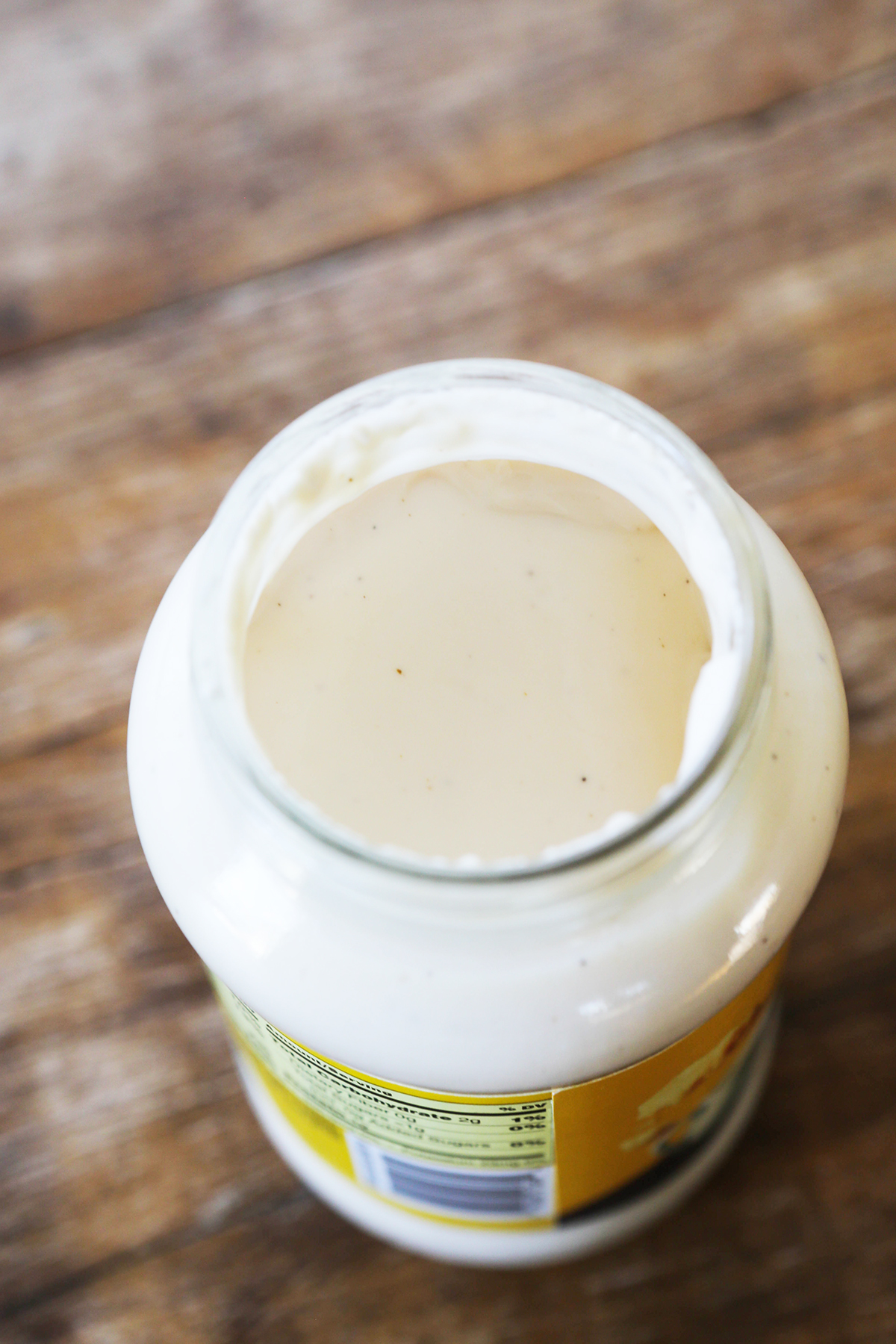 Looking down into a jar of store-bought alfredo sauce.