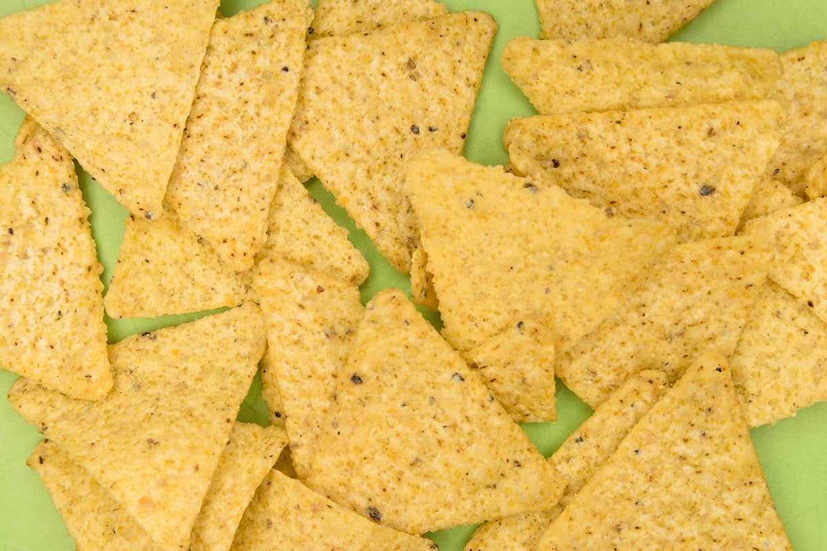 Tortilla chips lined up on a green counter.