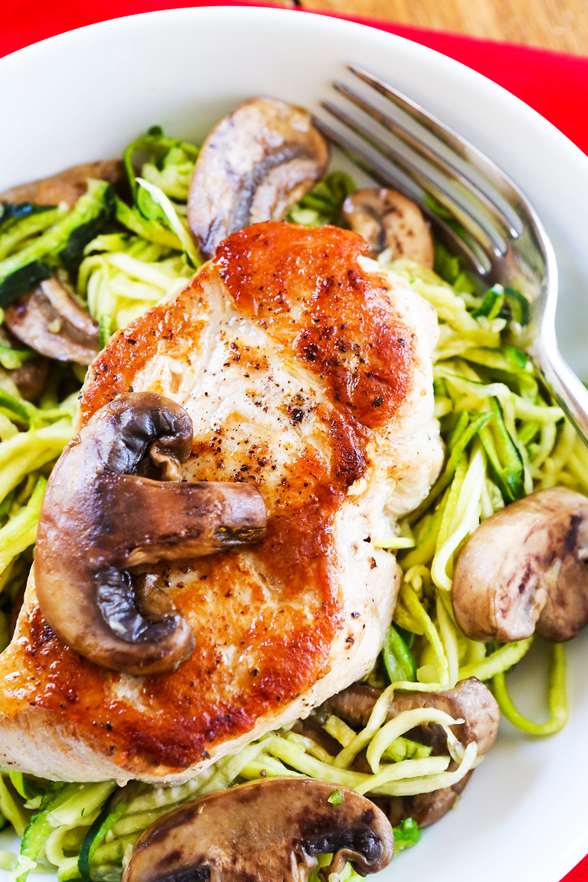 Top view of a seared pork chop with a mushroom slice sitting on top.