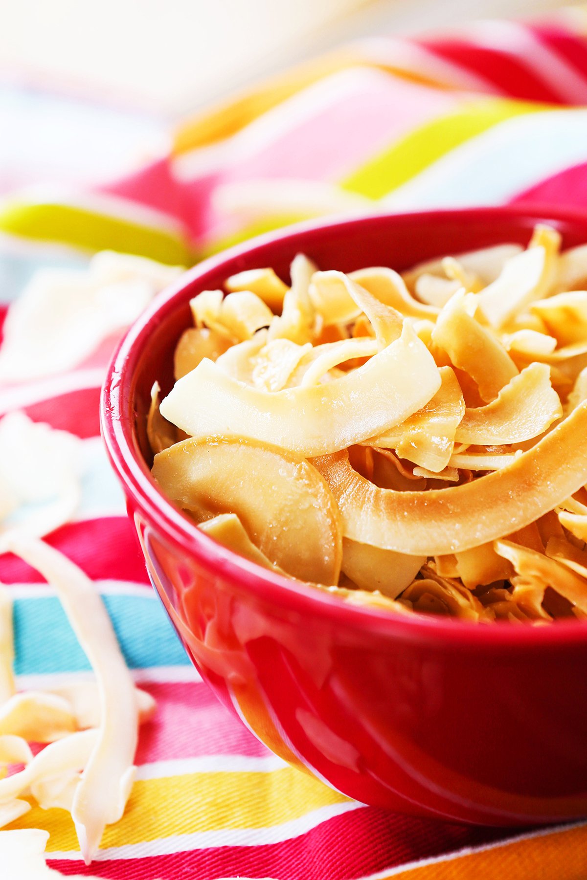 Red bowl filled with toasted coconut chips.