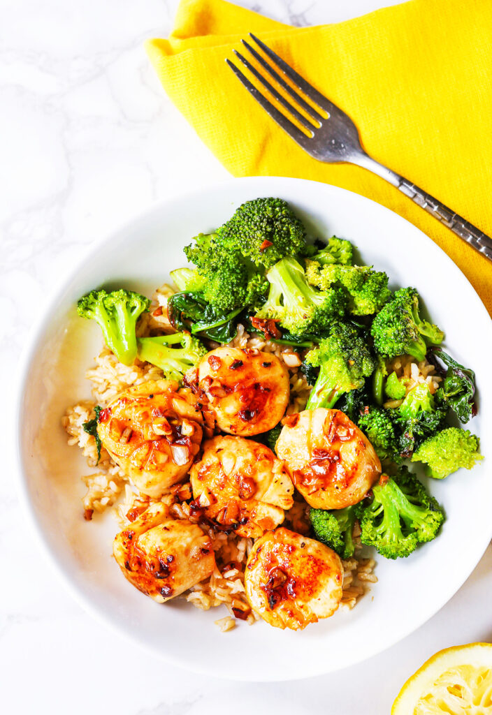 Plate of broccoli and pan seared scallops. 