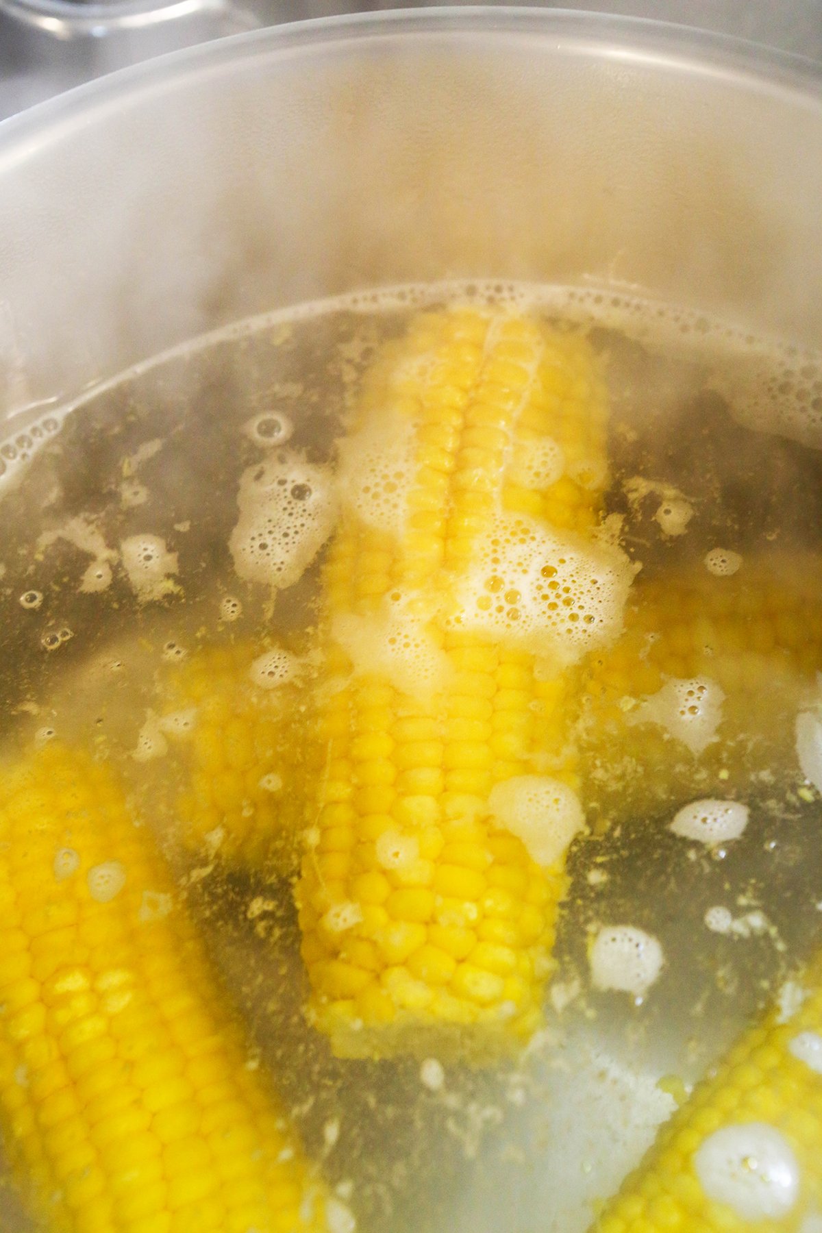 Corn on the cob being boiled in a large pot of water.