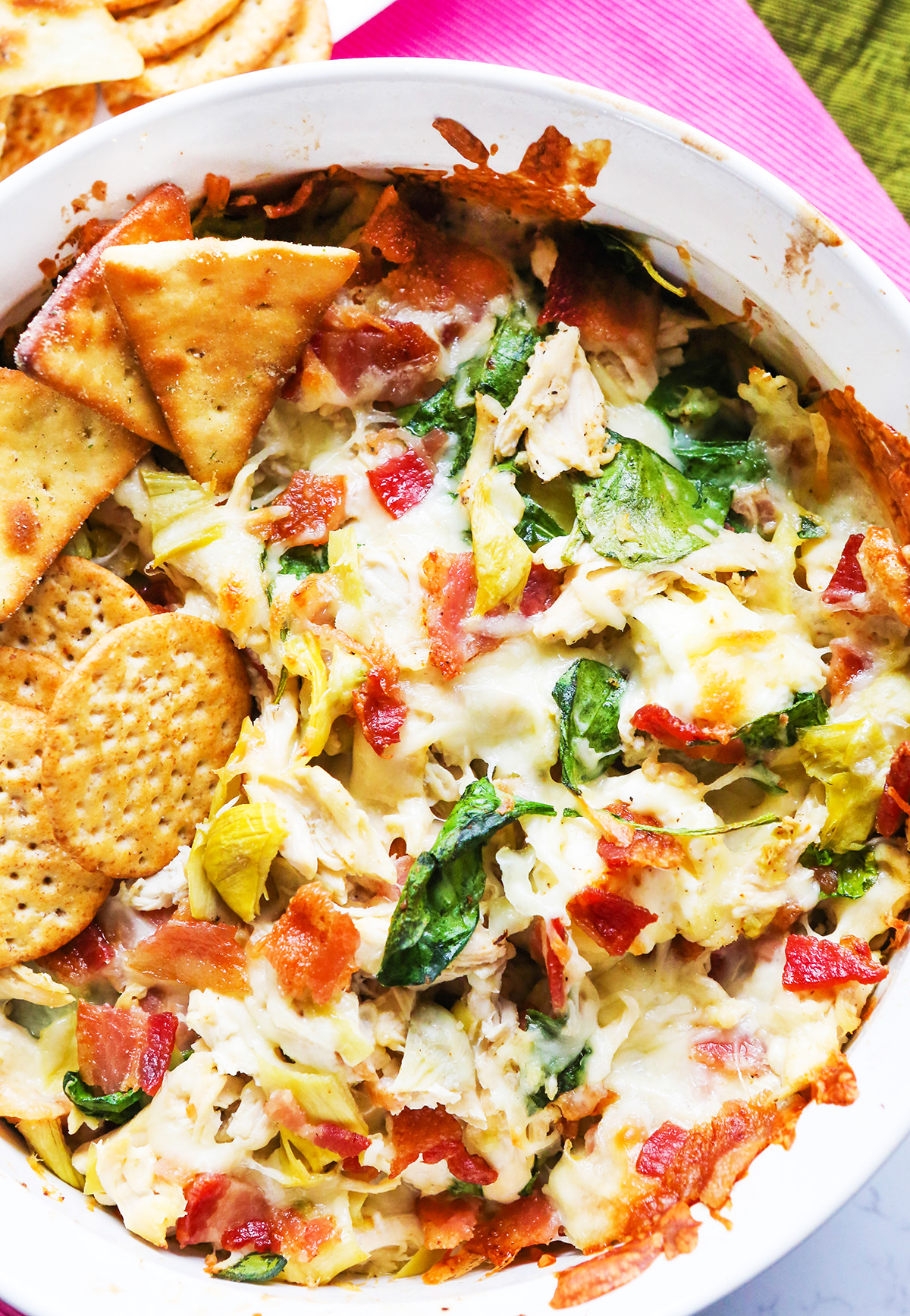 Top view of a hot dip with artichokes, bacon pieces and spinach.