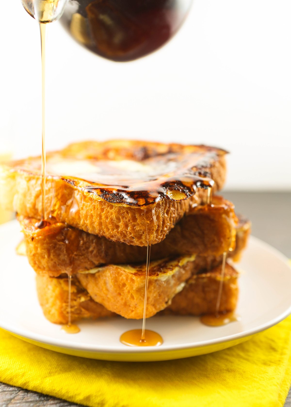 Syrup oozing down the sides of a stack of French toast.
