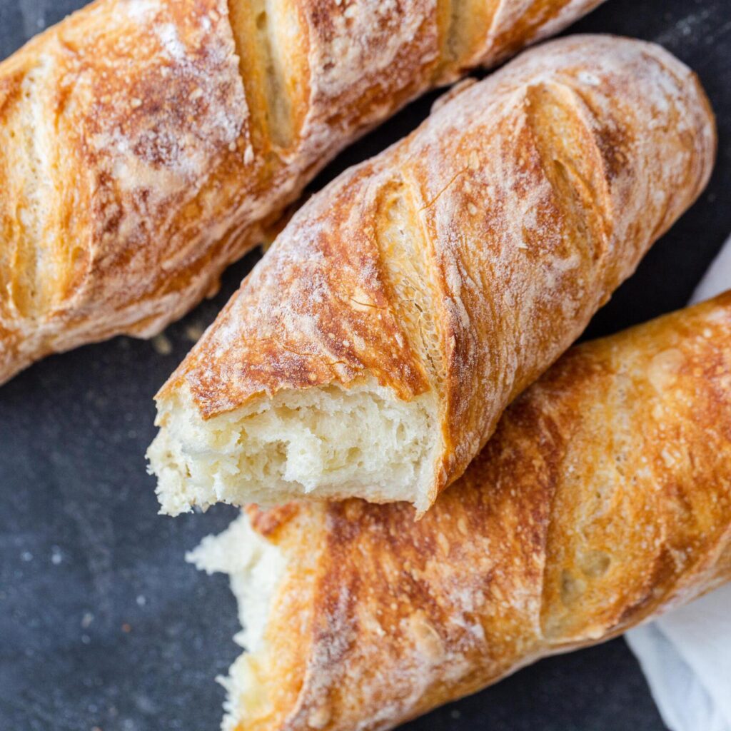 Crusty baguettes broken in half on top of one another. 