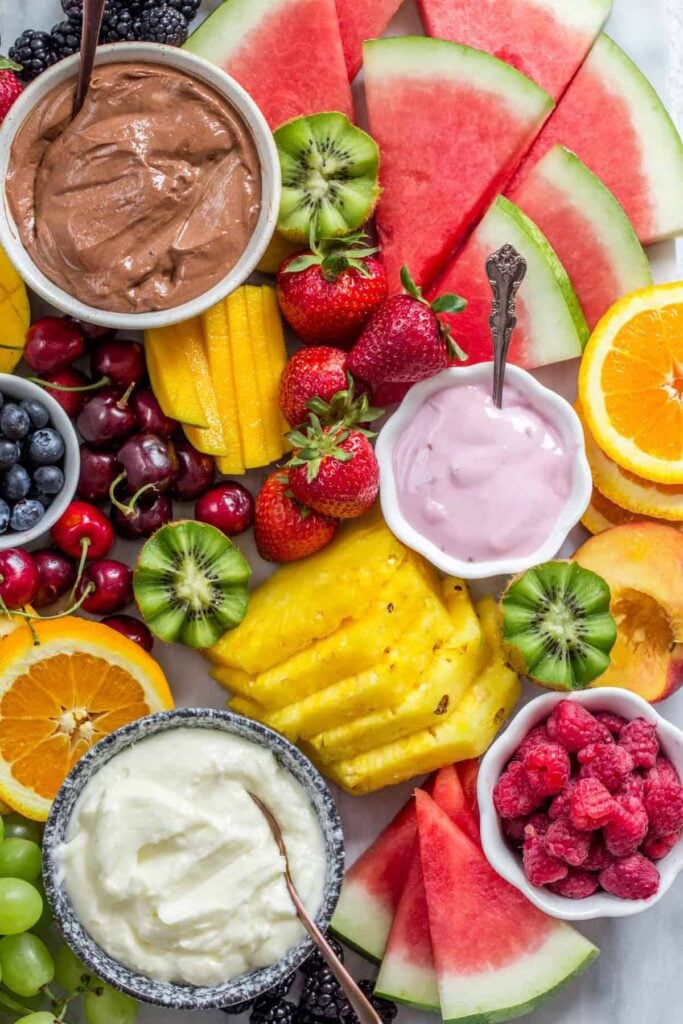 Ultimate fruit platter with yogurt and dips in small bowls. 