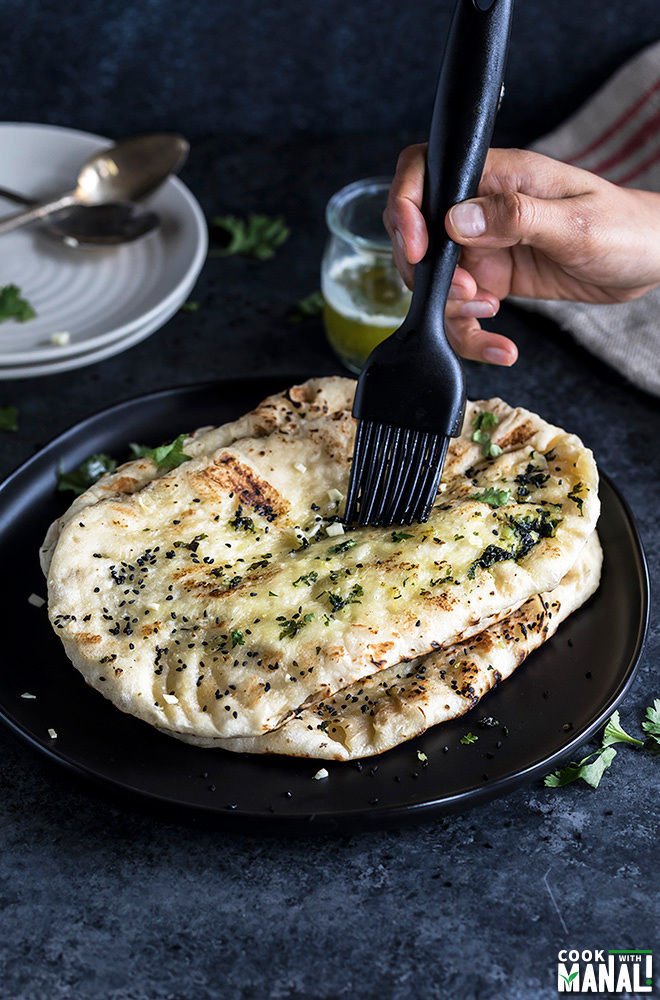 Naan bread with garlic and herbs being brushed on top.