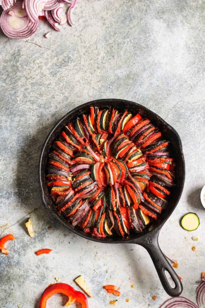 Cast iron skillet with colorful ratatouille baked inside. 