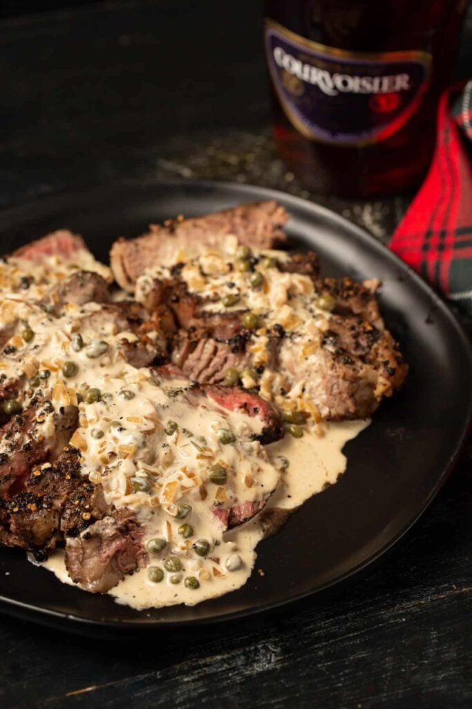 Steak Au Poivre on a plate with a creamy sauce over the top. 