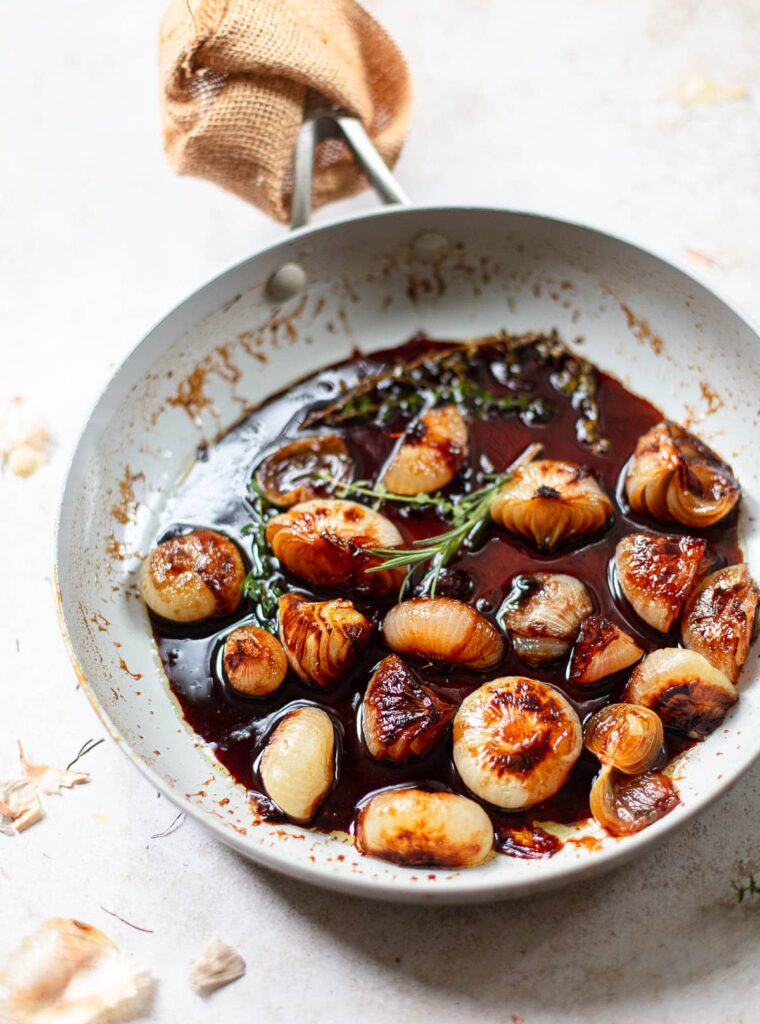 Cipollini onions in a saute pan with juice from ingredients flavoring it.