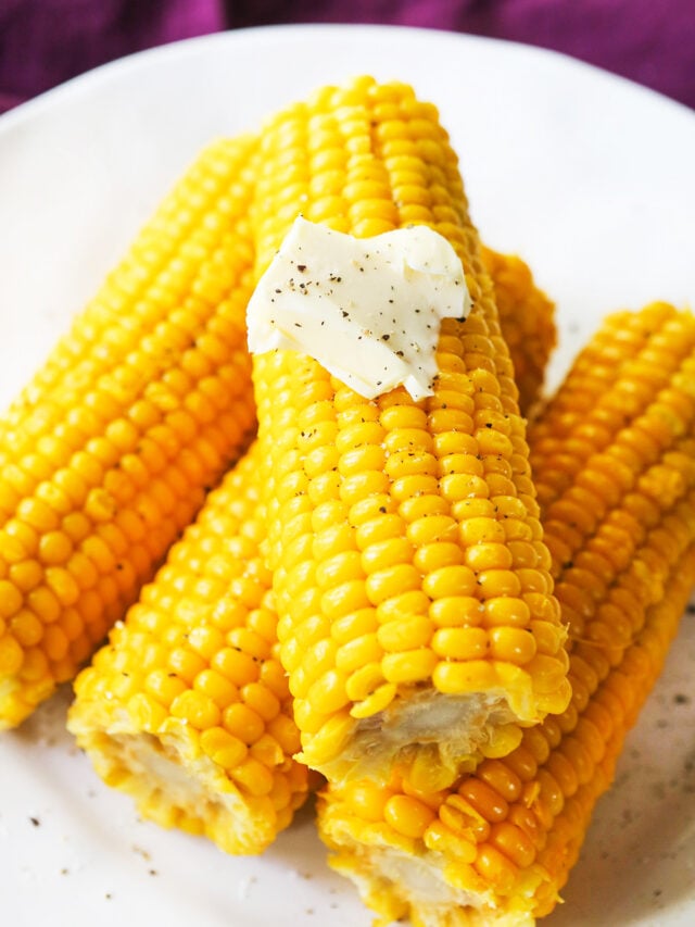 4 corn on the cob pieces, stacked on a plate with a pat of butter on top.