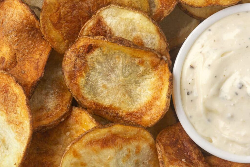 Air fried potato chips next to some dipping sauce. 