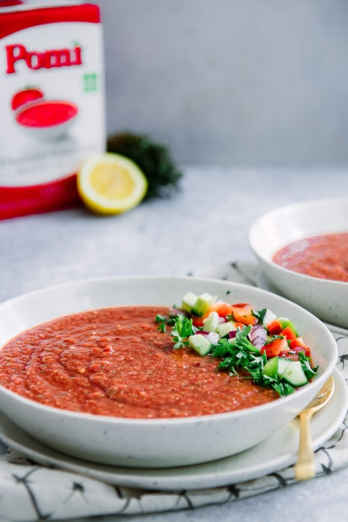 Bowl of spicy gazpacho with garnish on top. 