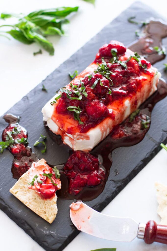 Cutting board with basil strawberry cream cheese dip with balsamic vinegar. 