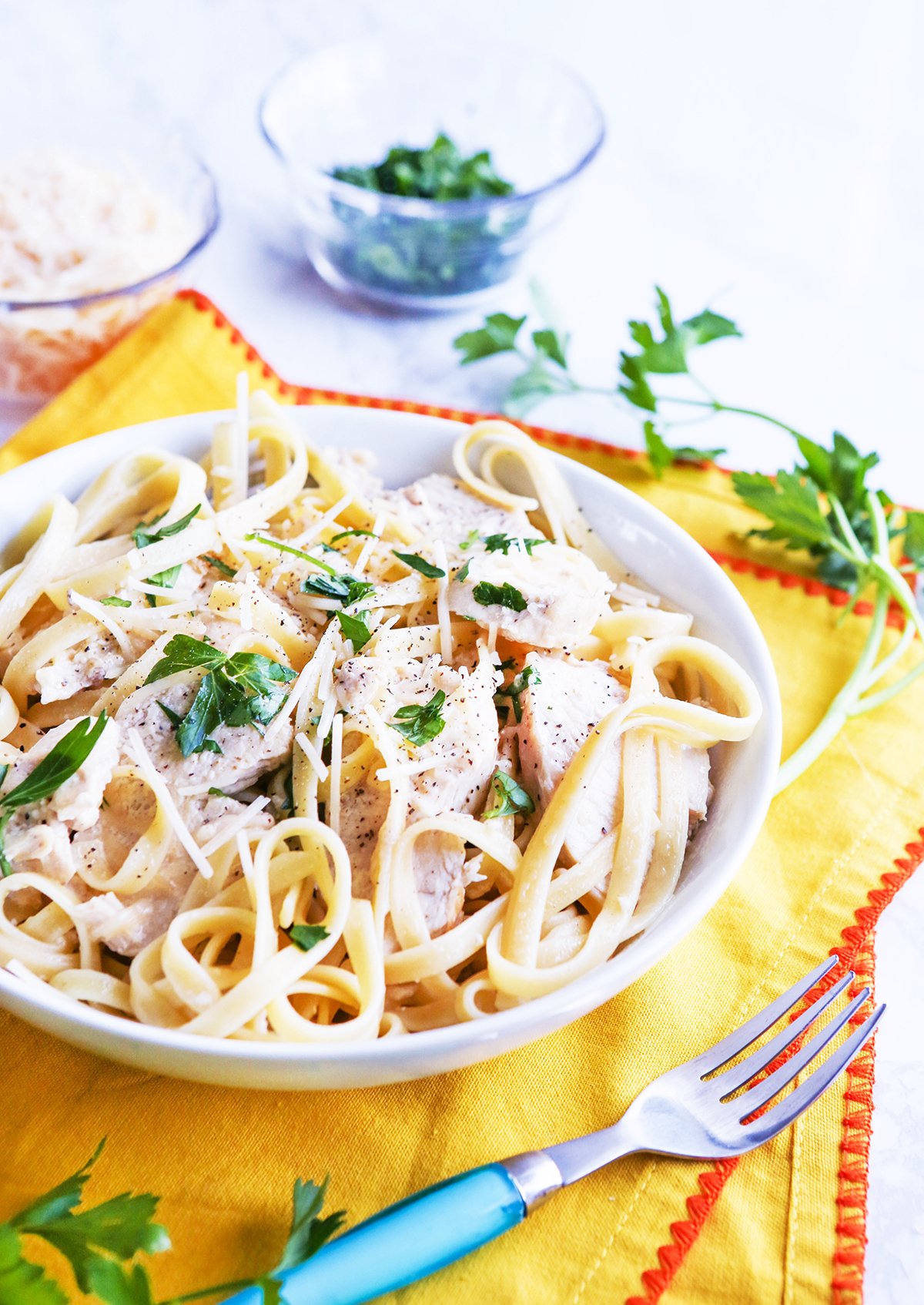 Bowl of chicken fettuccine alfredo topped with chopped parsley.