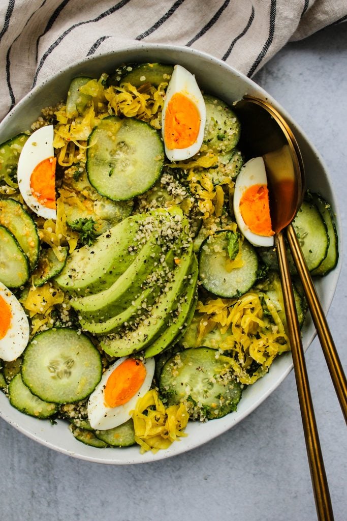 Easy avocado salad with cucumber and quinoa in a bowl with serving spoons tucked in.