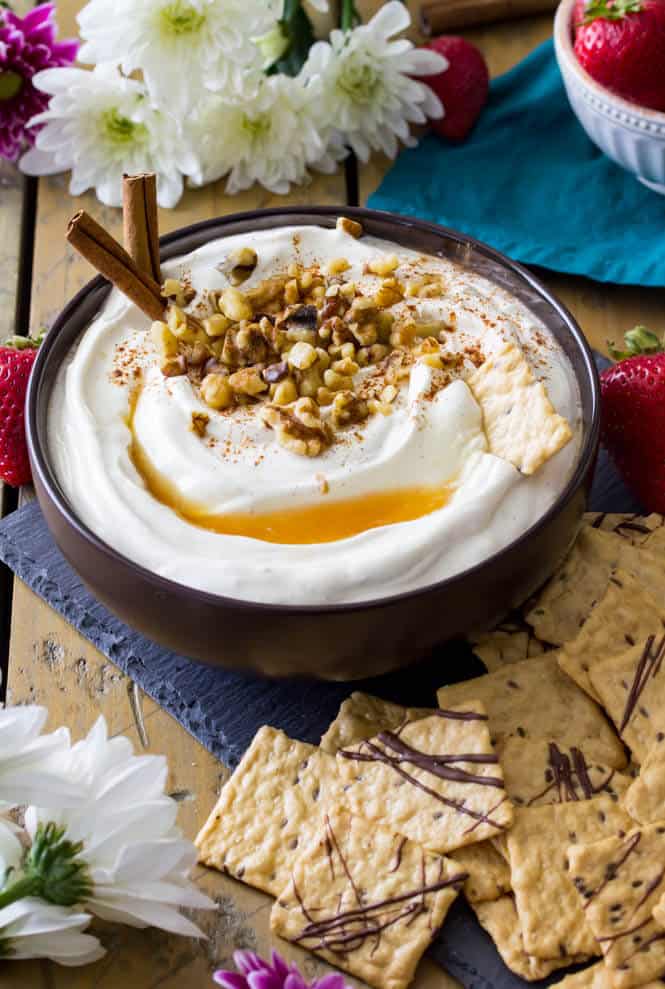 Baklava dip in a bowl with nuts and cinnamon sticks garnished on top. 