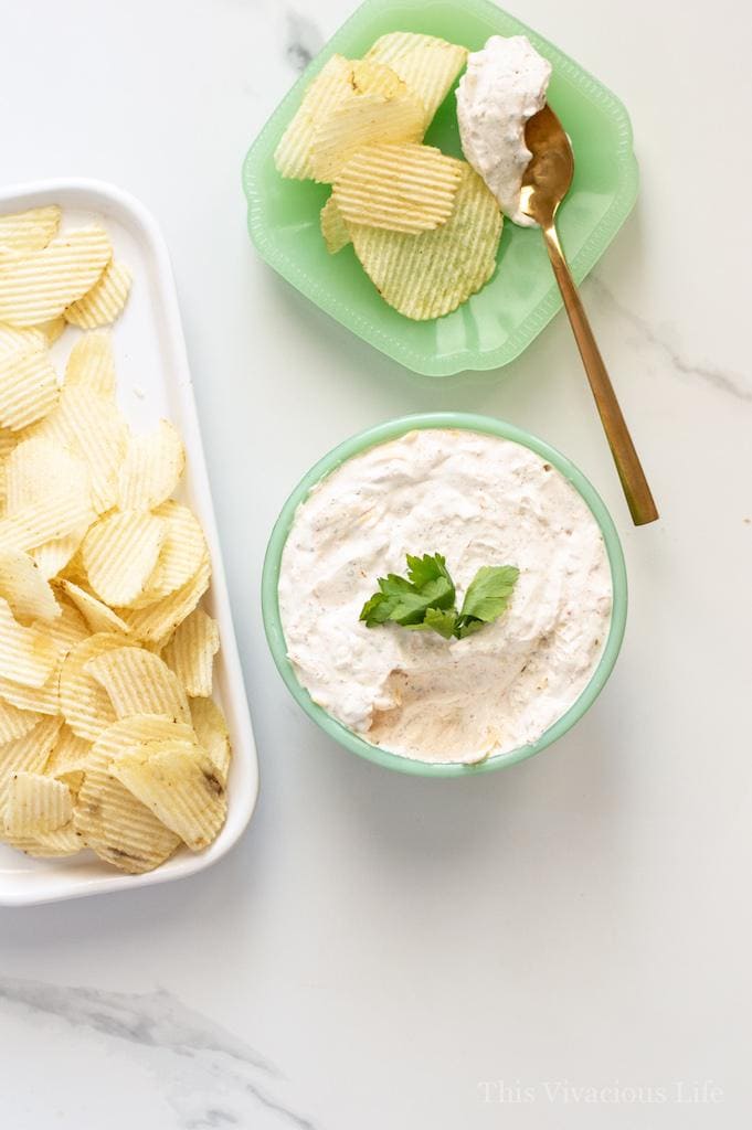 Sour cream chip dip in a bowl next to a bowl of chips. 