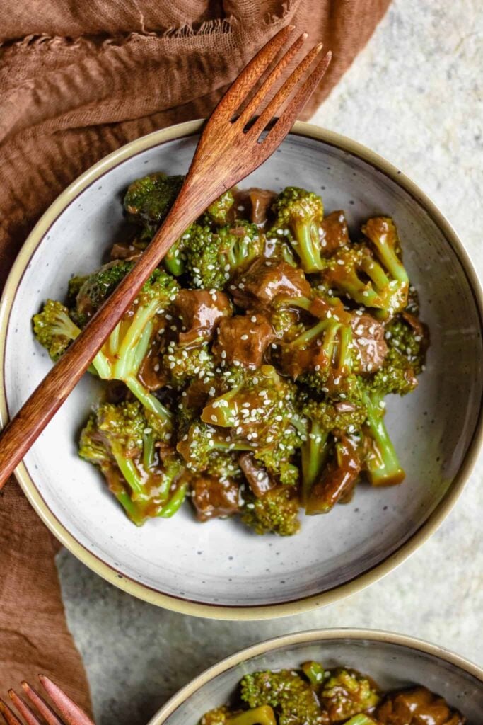 Bowl of beef and broccoli in a bowl with sesame seeds sprinkled on top. 