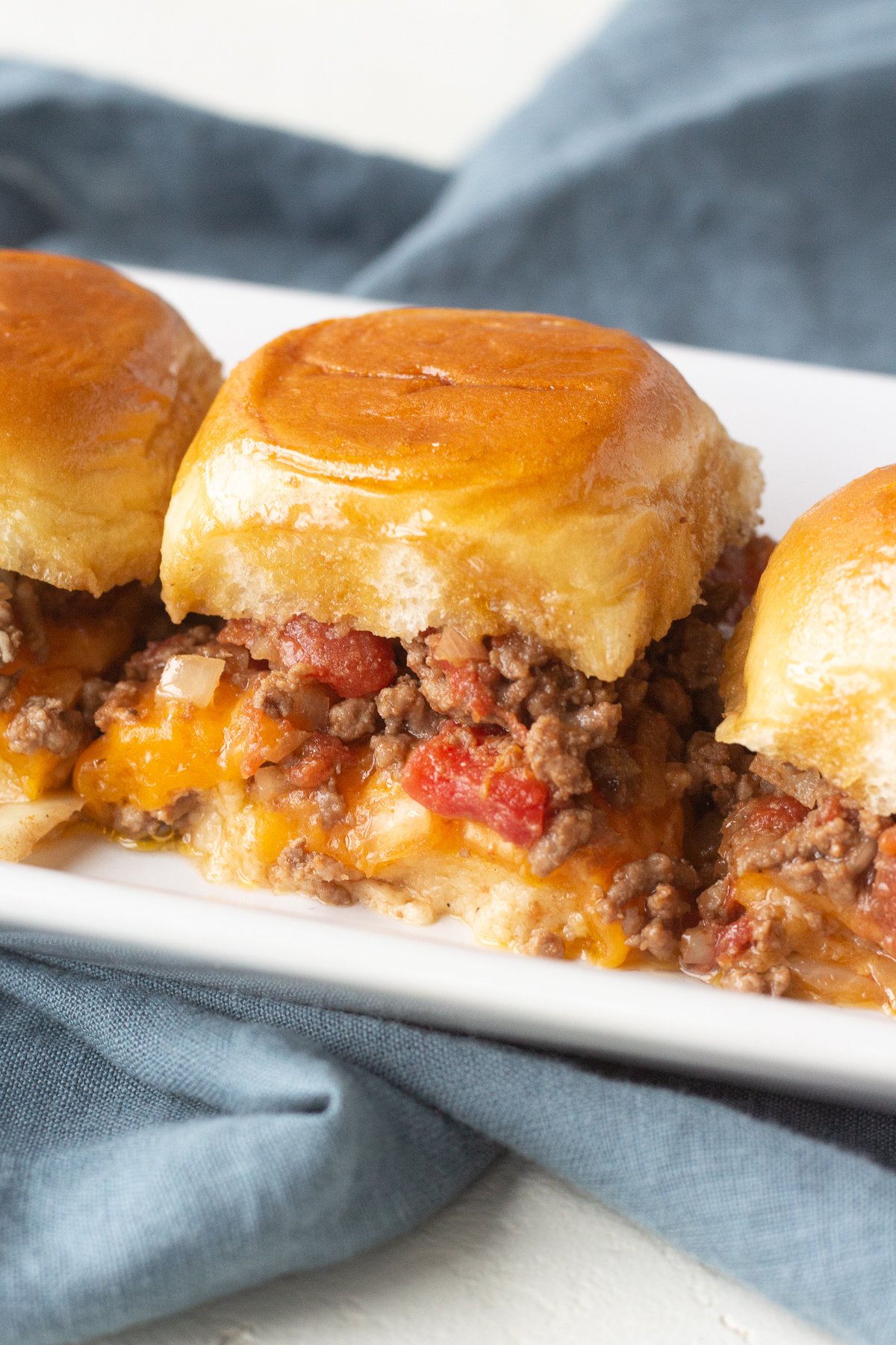 Ground beef sliders lined up on a long serving platter.