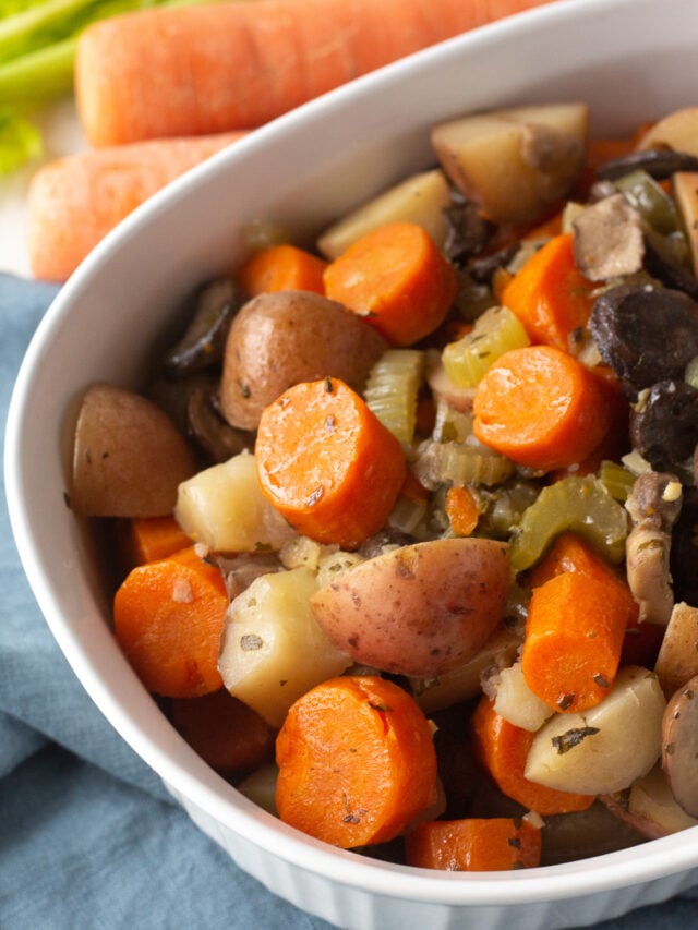Serving bowl filled with cooked carrots, potatoes and mushrooms.