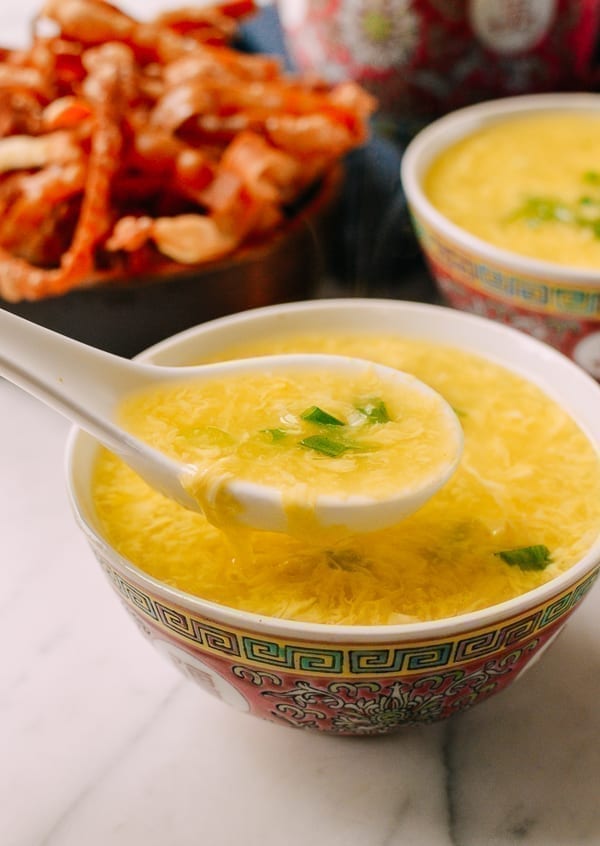 Chinese soup spoon ladling up a spoonful of egg drop soup out of a bowl. 