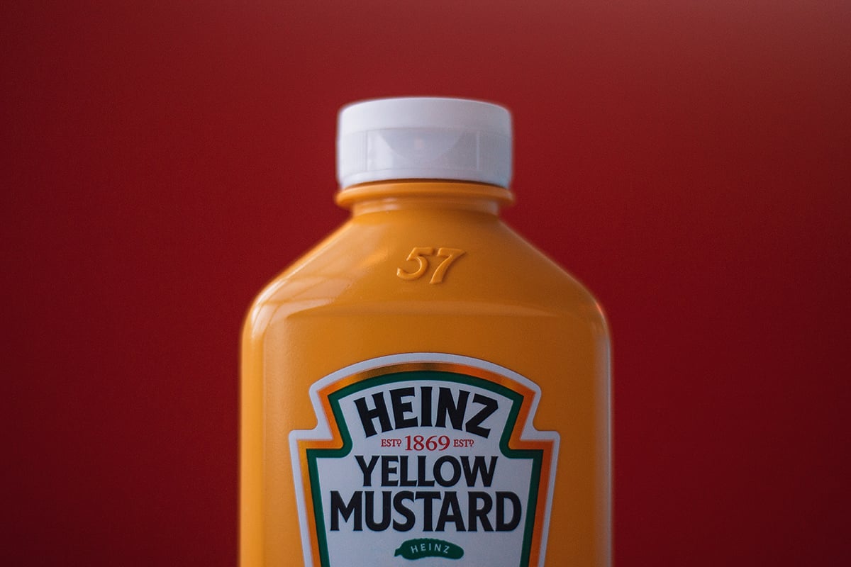 Bottle of Heinz mustard with a red background.