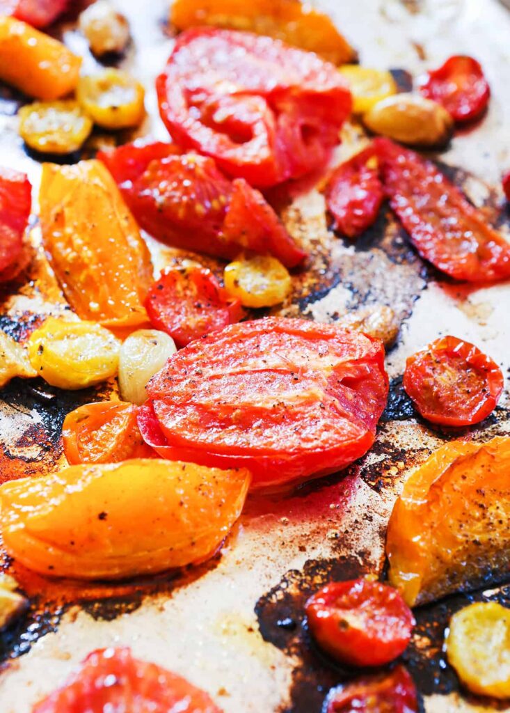 Roasted roma tomatoes lined up on a baking sheet.