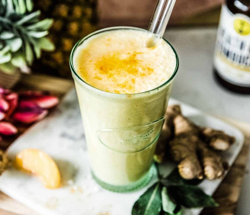 Sauerkraut green smoothie with fresh ginger sitting next to the glass.