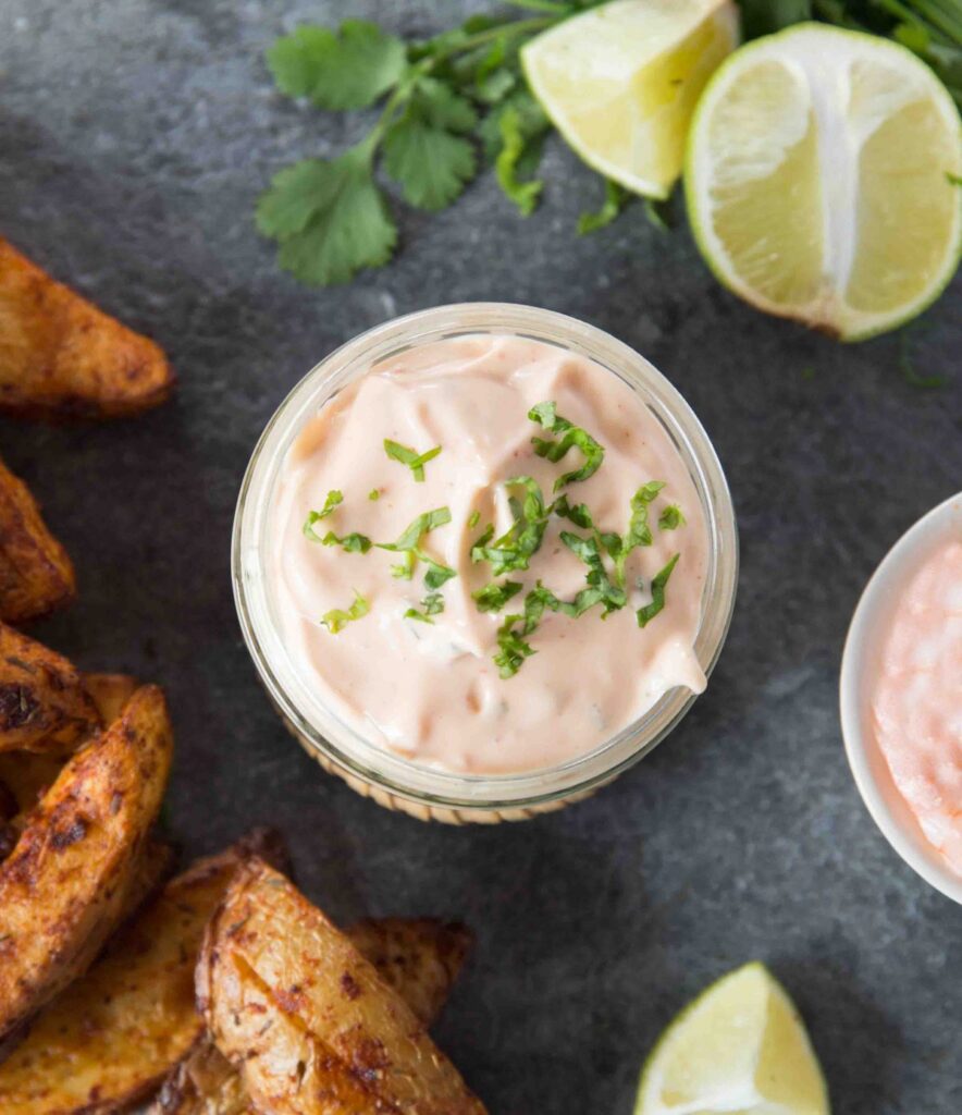 Sriracha Lime Mayo Dip in a glass container and sliced limes to the side. 