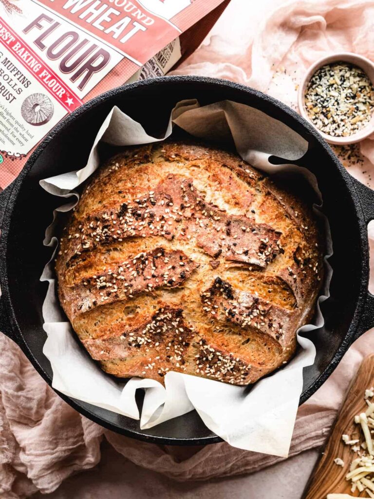 Cast iron skillet with a loaf of dutch oven cheddar and everything bagel seasoning. 