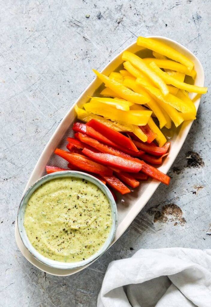 Zucchini dip with mint on a serving platter with cut up colorful sweet pepper slices. 