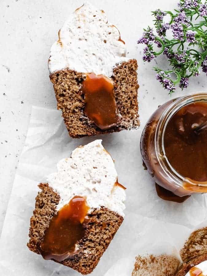 Caramel filled churro cupcakes with whipped cream on top, cut in half so you can see the caramel filling. 