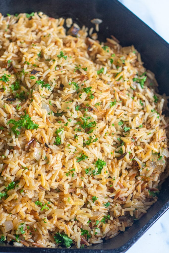 Rice pilaf served in a big bowl garnished with parsley. 