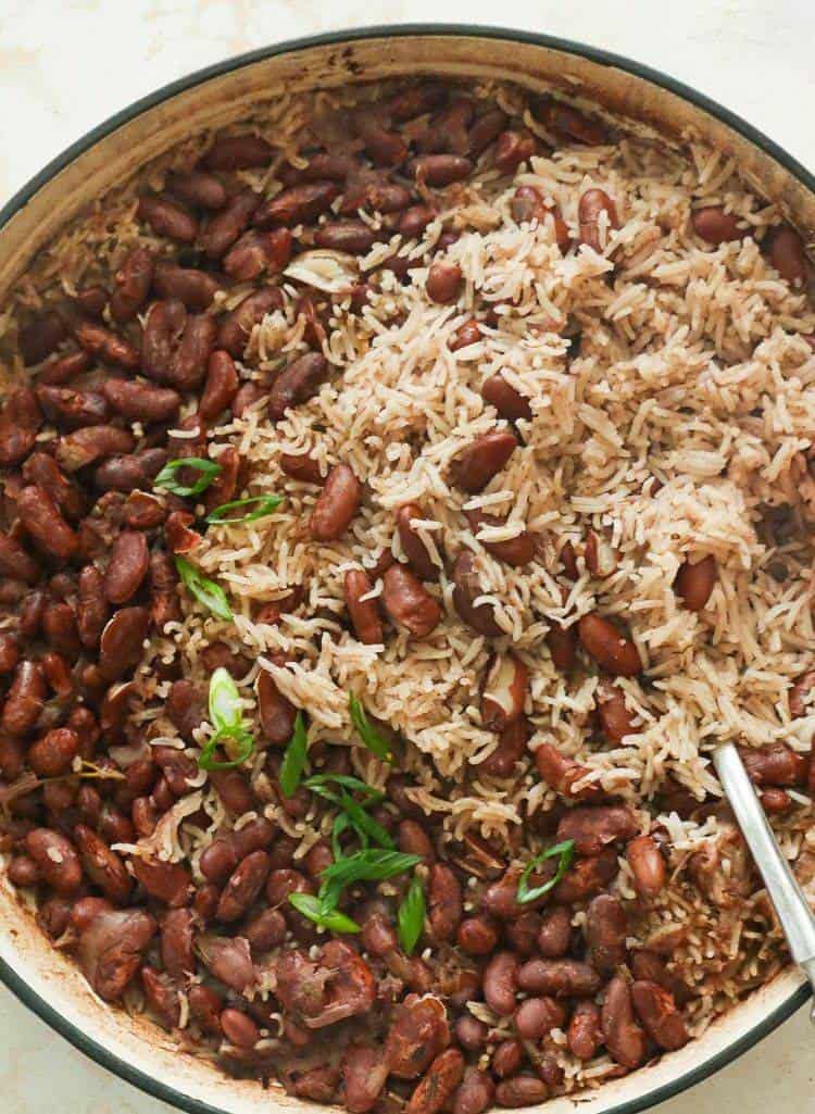Big pan of Jamaican rice and peas with a serving spoon inside. 