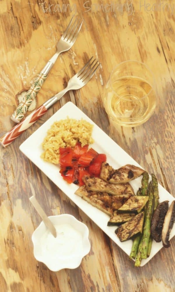 Grilled vegetables with jerk seasoning on them and a glass of wine by the plate. 
