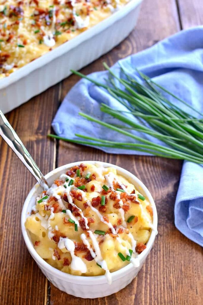 Small bowl of loaded macaroni and cheese sitting in front of the baked serving dish. 