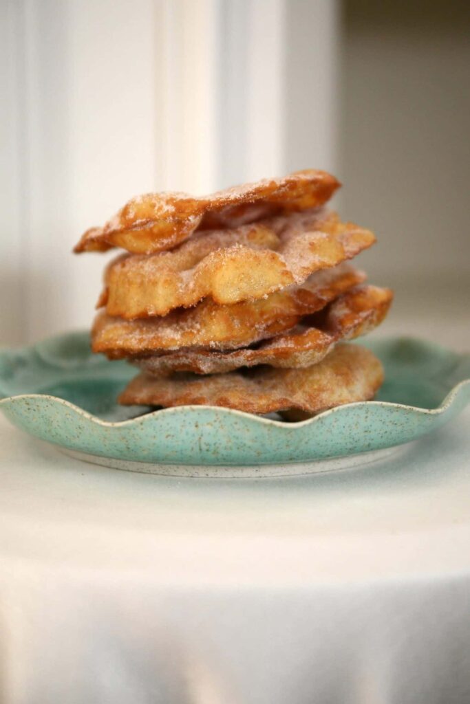 Buñuelos stacked and served on a pretty green plate. 