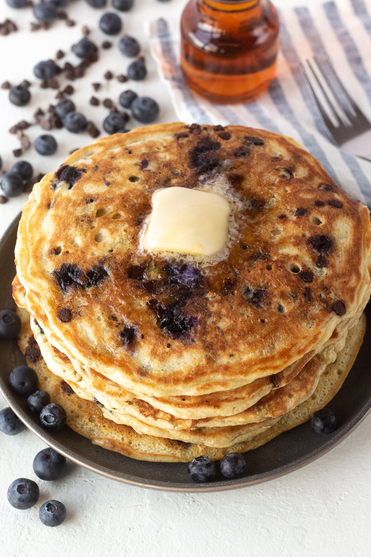 Stack of blueberry chocolate chip pancakes with melted butter on top.