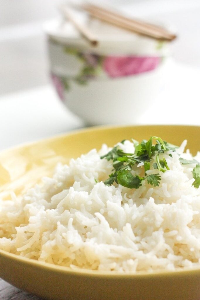 Serving bowl filled with coconut rice and garnished with chopped cilantro. 