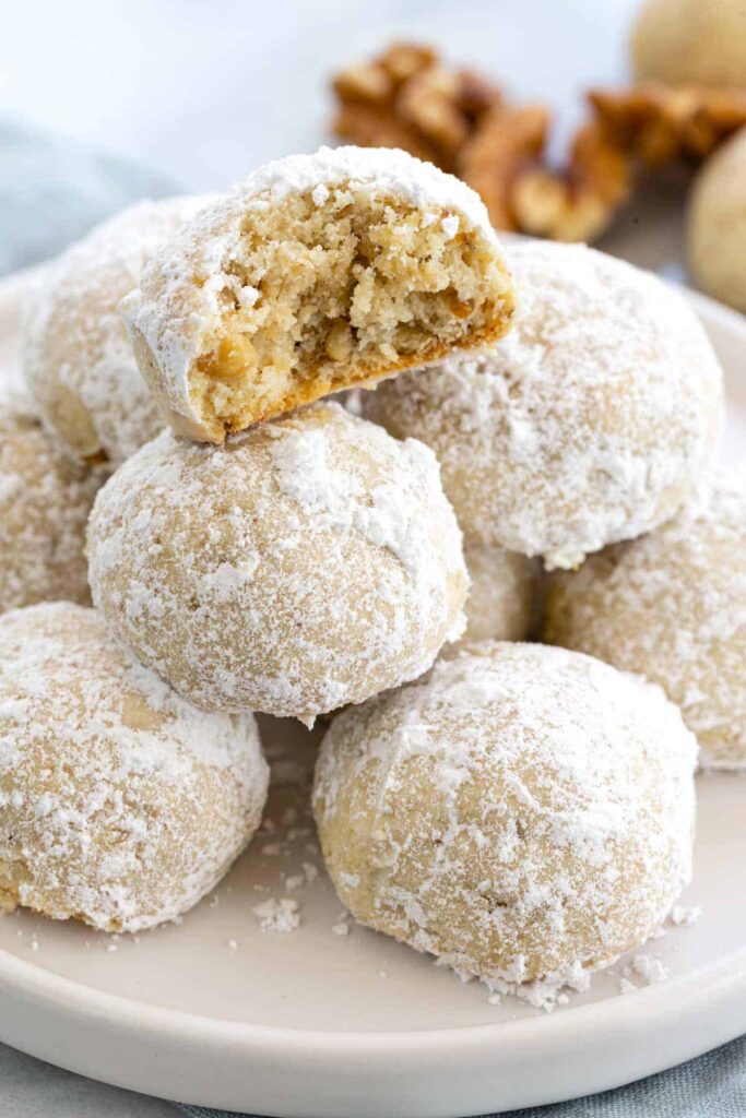 Mexican wedding cookies piled up with one half eaten on top. 