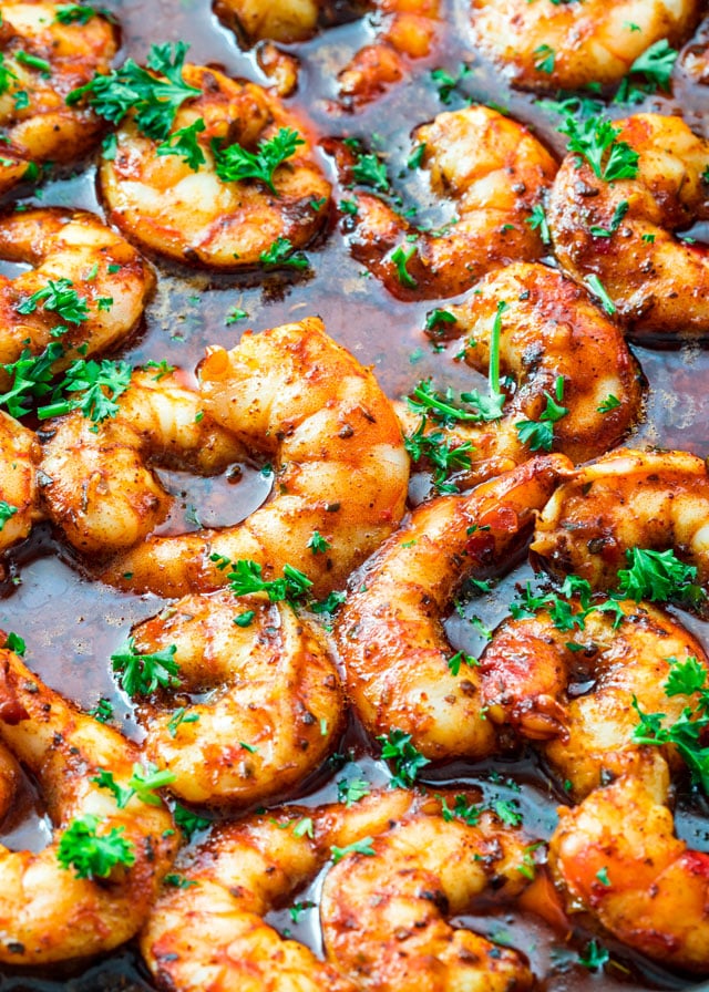 A pan of spicy cooked shrimp with diced Italian parsley. 