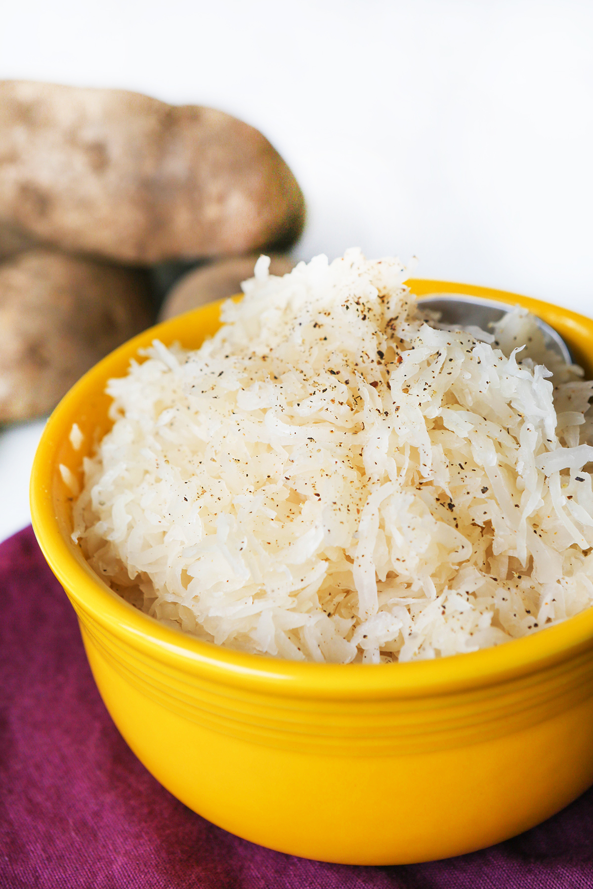 Yellow bowl filled with sauerkraut with pepper sprinkled on top.