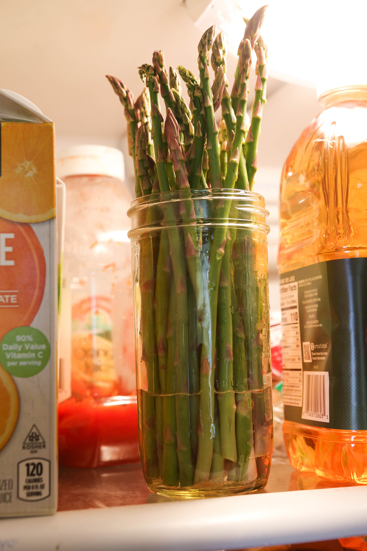 Asparagus spears in a jar with water in the bottom, sitting in the fridge.