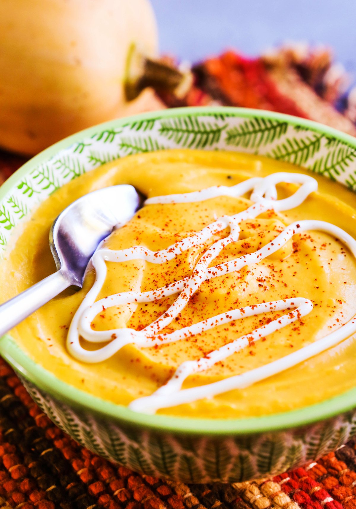 Bowl of butternut squash soup with a spoon inside.