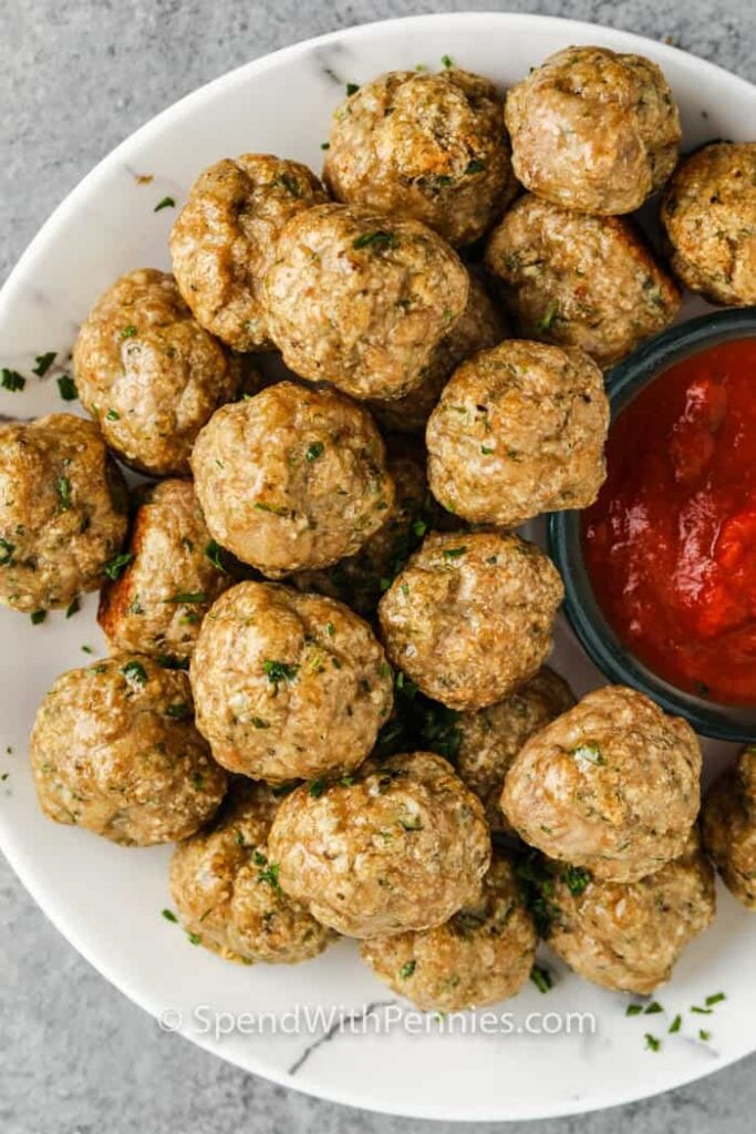 Plate full of chicken meatballs served with a dish of marinara. 