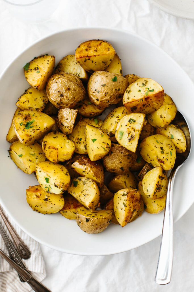 Garlic herb potatoes in a bowl with a serving spoon tucked into it. 