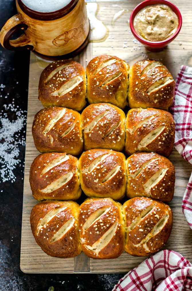 Pretzel rolls sitting on top of a cuttinb board. 