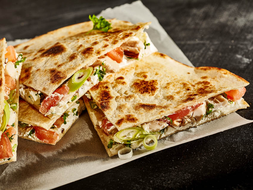 Loaded quesadillas cut into squares and sitting on a platter.